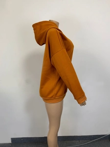 Side view of ginger yellow oversized hoodie showing ribbed cuffs and drop shoulder detail