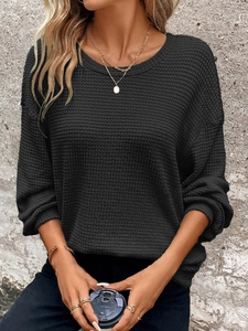 Close-up of black waffle knit texture on a loose crewneck sweatshirt with ribbed cuffs