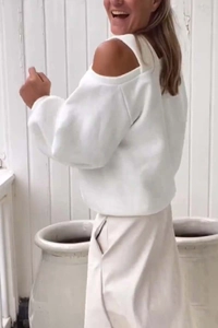 Detail view of the cold shoulder cut-out and lantern sleeves on a white fleece sweatshirt