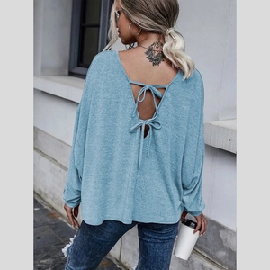 Détail du haut en tricot bleu clair montrant le dos ouvert en V avec des nœuds rubans