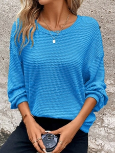 Close-up of bright blue waffle knit fabric texture on a loose long-sleeved sweatshirt