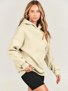 Detail view of oversized beige hoodie with dropped shoulders and black ribbed cycling shorts