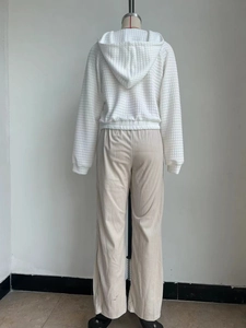 Back view of a white waffle knit hoodie paired with beige corduroy wide-leg pants for women