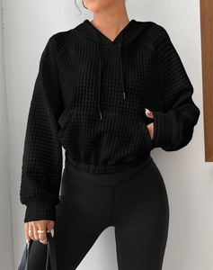 Detail of black waffle knit hoodie showing quilted diamond texture and kangaroo pocket
