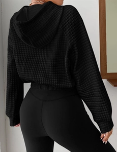 Detailed back view of women's black hooded waffle knit sweatshirt with ribbed hem