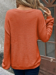 Detail of orange waffle knit sweater with drop shoulder design and textured fabric