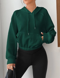 Detail of waffle-knit fabric and kangaroo pocket on dark green drawstring hoodie