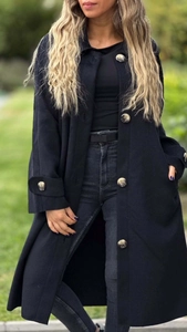 Dettaglio del cappotto di lana nero con bottoni ambrati e cinturini ai polsi