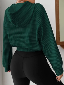 Detail view of dark green waffle knit texture on a loose hooded sweatshirt for women