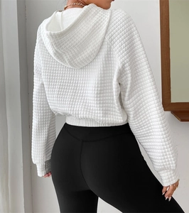Detail view of white waffle knit hoodie fabric showing textured pattern on model back