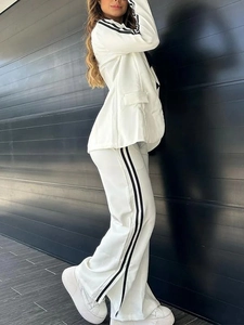 Detail of white blazer set with black side stripes and high waist wide leg trousers