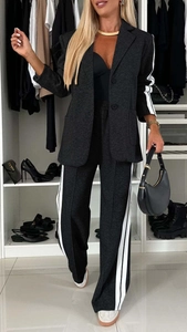 Detail of grey two-piece suit set featuring white side stripes on sleeves and wide-leg trousers