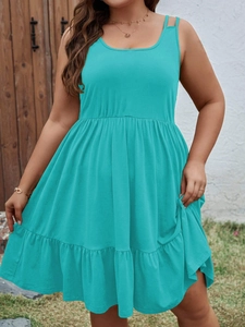 Detail of the high-waisted tiered hem and dual shoulder straps on the turquoise dress