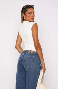 Close-up of the side ruched details and slim-fit fabric on the white sleeveless high-neck top