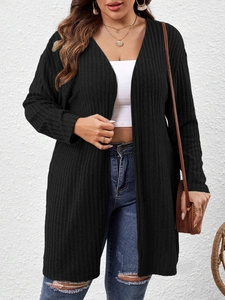 Dettaglio del cardigan lungo nero a costine abbinato a jeans casual e borsa in paglia