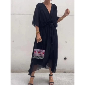 Detail view of black V-neck dress with batwing sleeves and asymmetrical layered hemline