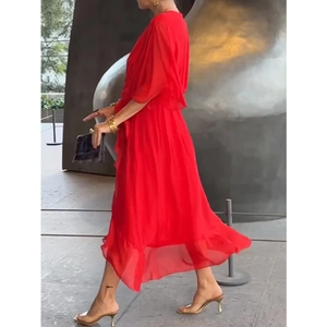 Detail of red pleated midi dress with puff sleeves and ruffled hem on a walking model