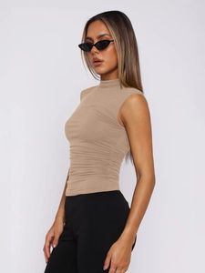 Detail of mock neck and ruched side draping on a slim-fit sleeveless camel top