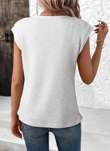 Détail d'un haut blanc en maille gaufrée avec col rond sans manches pour femme moderne