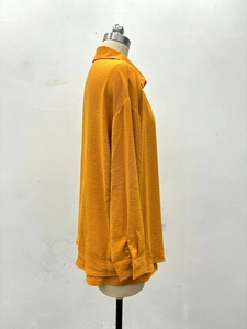 Détail d'un chemisier à manches longues jaune gingembre avec col à revers et tissu froissé