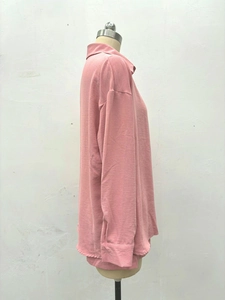 Détail du haut polo à manches longues rose poudré avec texture en maille et poignets côtelés