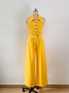 Detail view of bright yellow linen-textured vest and high-waist wide-leg trousers set