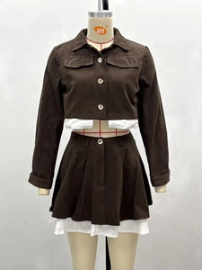 Detail view of brown long-sleeved jacket and pleated mini skirt with layered white hem design