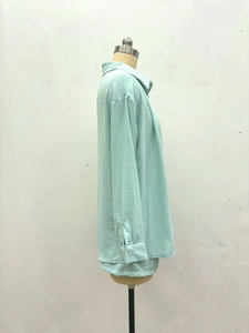 Détail latéral d'une chemise vert menthe en tissu texturé avec col et poignets boutonnés