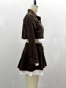Detail of a brown two-piece set featuring a cropped jacket and high-waist pleated mini skirt
