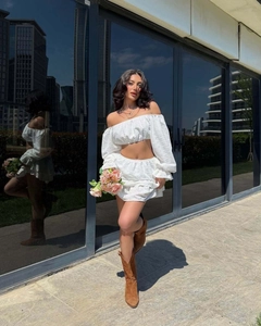 Détail d'un ensemble blanc deux pièces avec crop top bardot et mini-jupe à volants