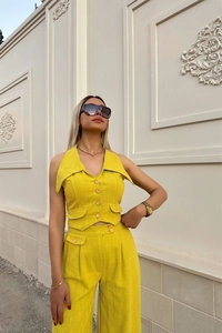 Detail of yellow sleeveless vest with wide-leg trousers in textured cotton linen fabric