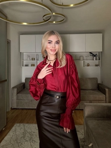 Detail of red satin blouse with lantern sleeves and high-waisted brown leather skirt