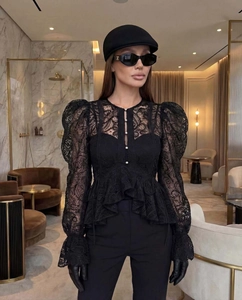 Détail du haut en dentelle noire avec manches bouffantes et boutons en perles chic