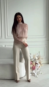 Detail of high-neck pleated chiffon blouse and high-waist trousers in an office setting
