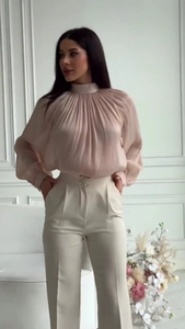 Close-up of elegant pleated long-sleeved blouse with high neck and cinched cuffs detail
