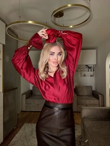 Close-up of wine red satin blouse with puff sleeves and brown leather pencil skirt