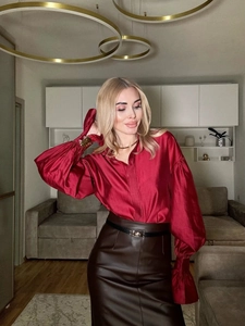 Detail of red silky long-sleeve blouse with lantern sleeves and buttoned cuffs