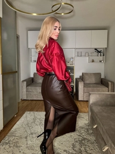 Detail view of red satin lantern sleeve blouse and brown faux leather slit skirt