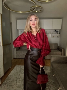 Detail of red satin long sleeve shirt with pleated lantern cuffs and brown leather skirt
