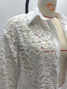 Close-up of white long sleeve shirt featuring intricate floral lace embroidery and collar
