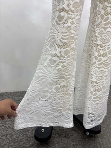 Detail of white wide-leg trousers featuring floral lace crochet and hollow-out texture