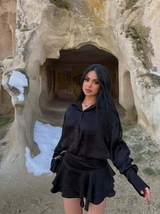 Dettaglio di un set elegante con camicia in raso nero e minigonna con volant chic