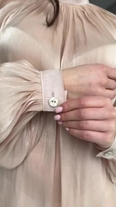 Close-up of pleated champagne chiffon sleeve with elegant mother-of-pearl button