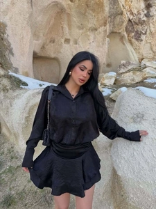Dettaglio del set di lusso in raso nero con camicia a maniche lunghe e gonna a balze