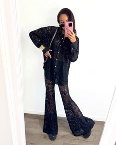 Close-up of elegant black lace shirt and flared trousers set with floral details