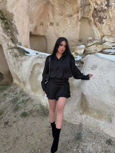Dettaglio di un elegante abito a camicia in raso nero con orlo a balze e finitura lucida
