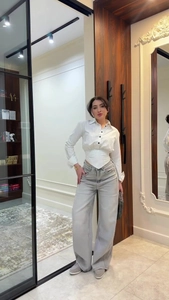 Detail of white striped corset shirt with cinched waist and wide-leg denim jeans