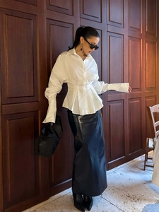 Detail of white pleated waist shirt with long tight cuffs paired with black leather skirt