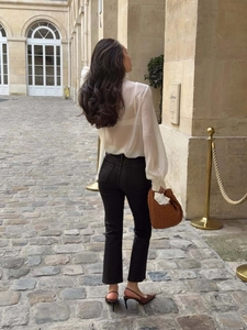 Vue arrière d'un chemisier blanc avec un sac à main en cuir tressé marron en ville