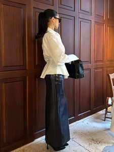 Detail of white pleated waist shirt paired with a sleek black glossy midi skirt